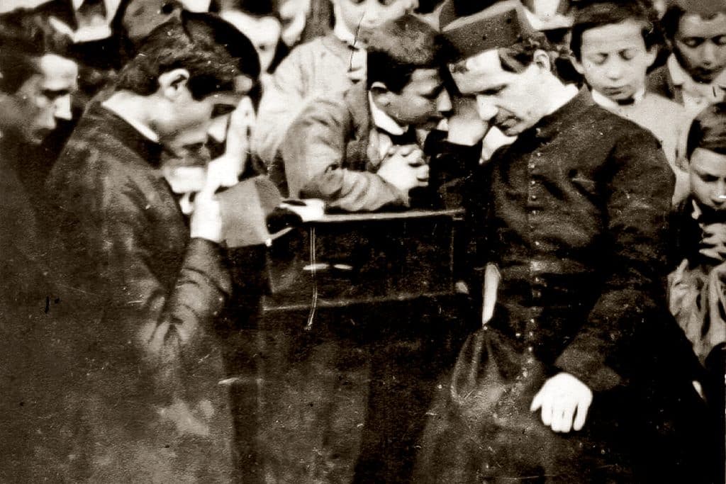 Photographie de Don Bosco écoutant un enfant en confession.